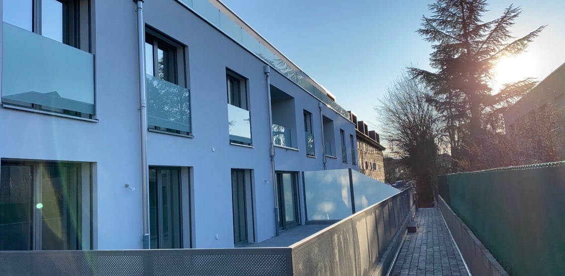 Façade en contre-jour : garde-corps vitrés et parapet en tôle perforée — Sous-Balme, Veyrier (GE)