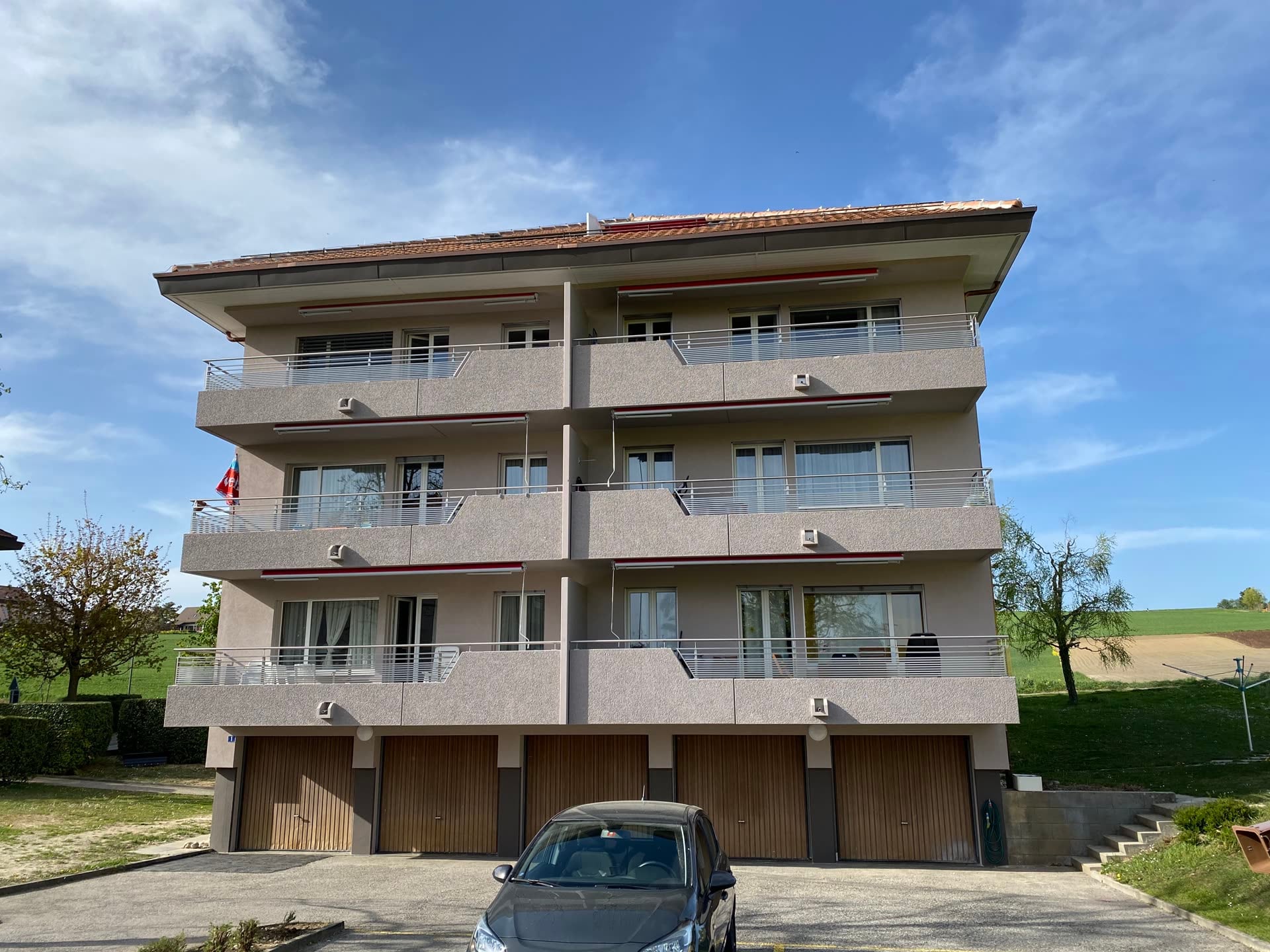 Façade principale : balcons à garde-corps métalliques au-dessus des garages — Etangs 1 & 2, Penthalaz (VD)